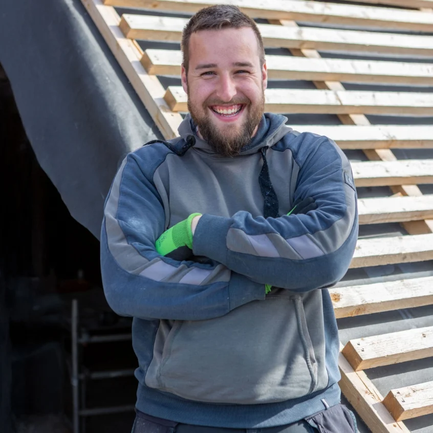 Ein Dachdecker vor einer Dachbaustelle