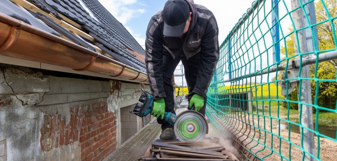 Ein Dachdecker sägt einen Dachziegel